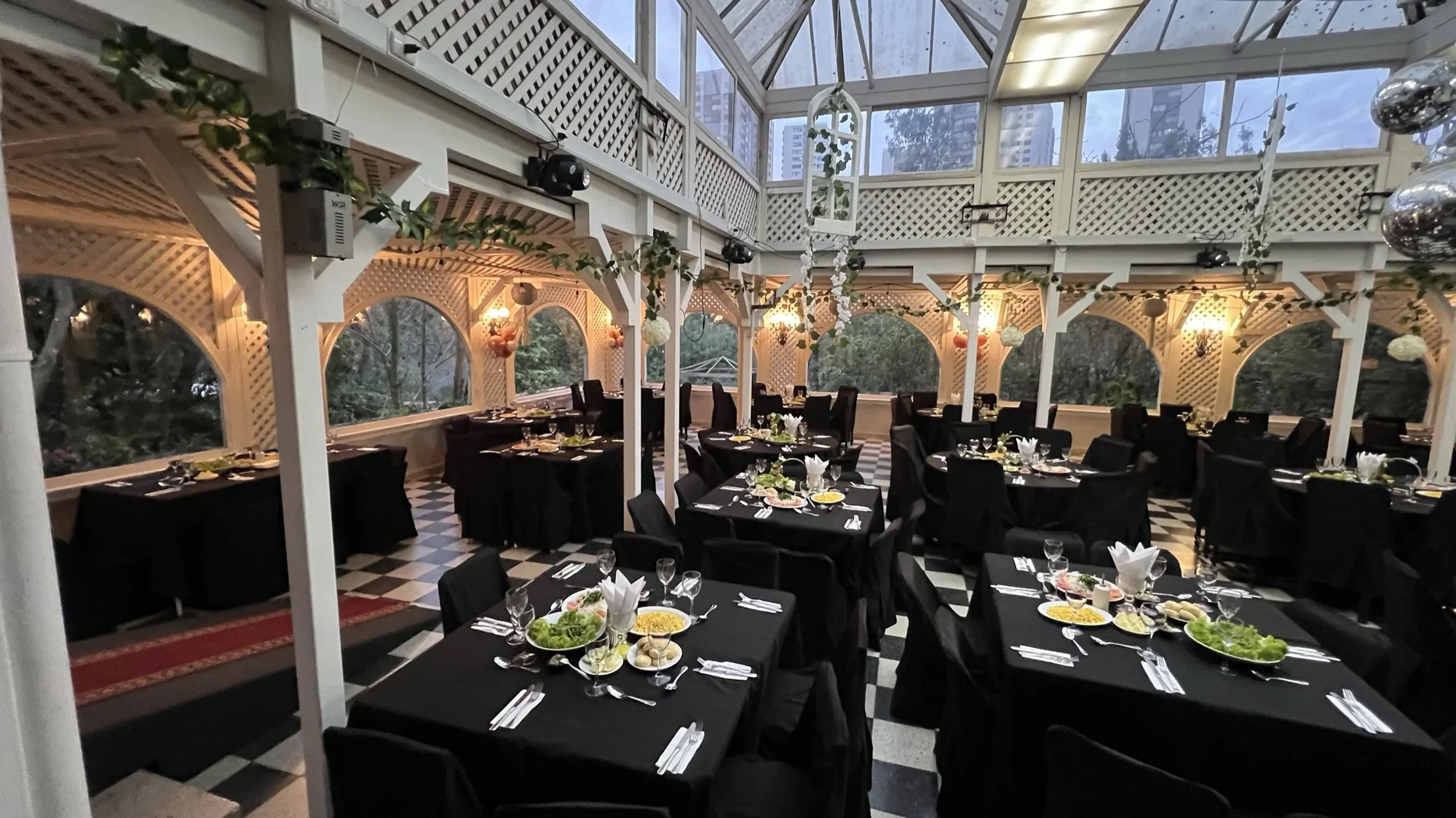 Salón dispuesto con mesas negras para una celebración